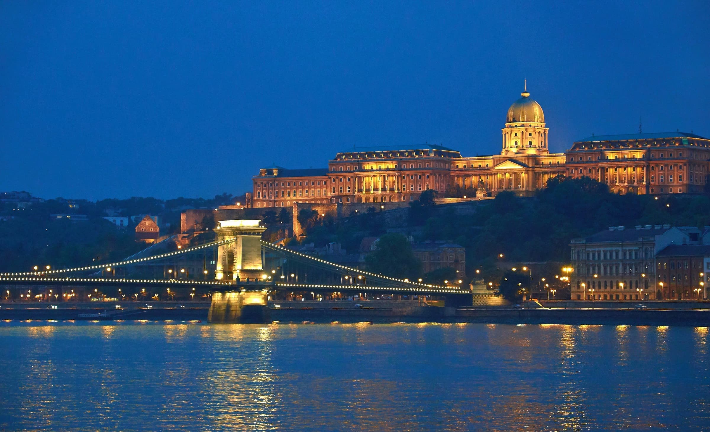 Buda Castle glowing above the Danube at blue hour